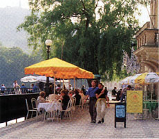 A sidewalk cafe by the Vlatava River beckons passersby